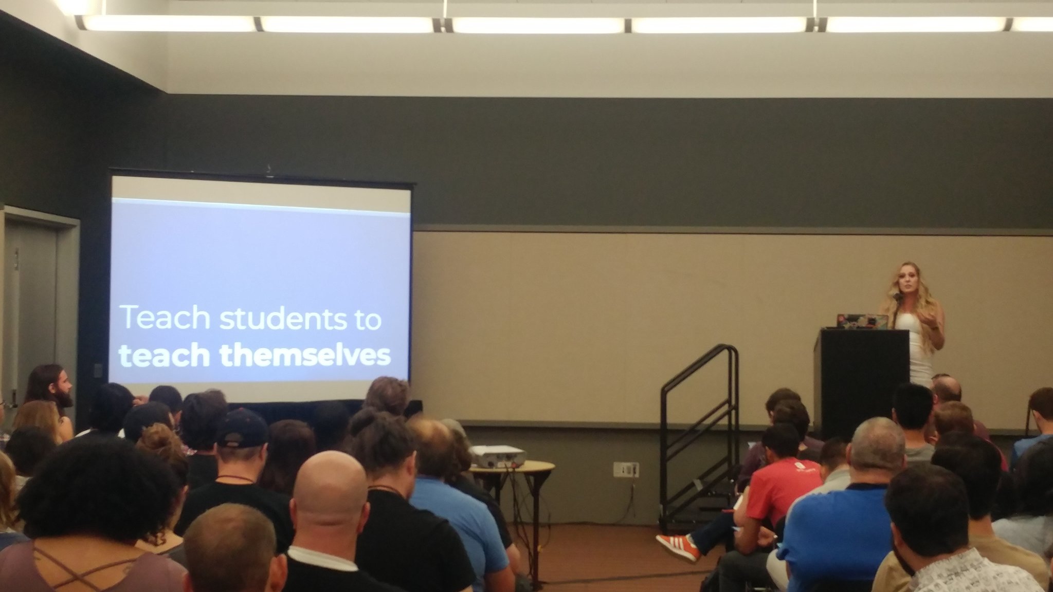 speaking to a crowd with the slide 'tech students to teach themselves'